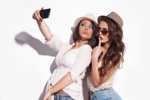 two young women taking selfie with mobile phone